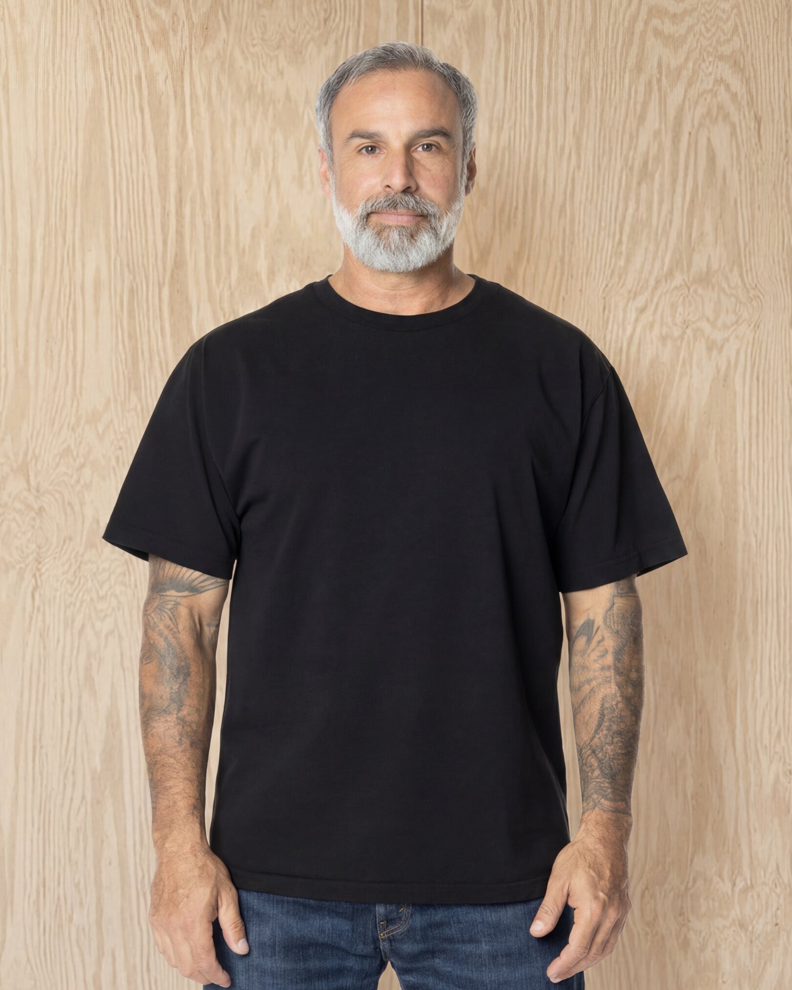 Man wearing a black Mock Neck t-shirt against a wood background. Model is 5'11", 198lbs wearing size L