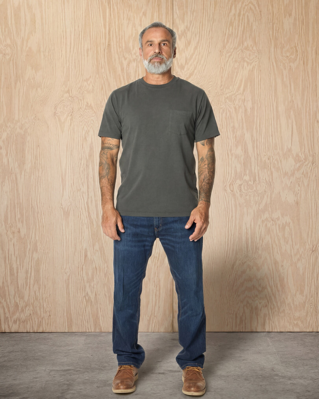 Man wearing a Steel Grey Pocket t-shirt and jeans against a wood background. Model is 5'11", 198lbs wearing size L