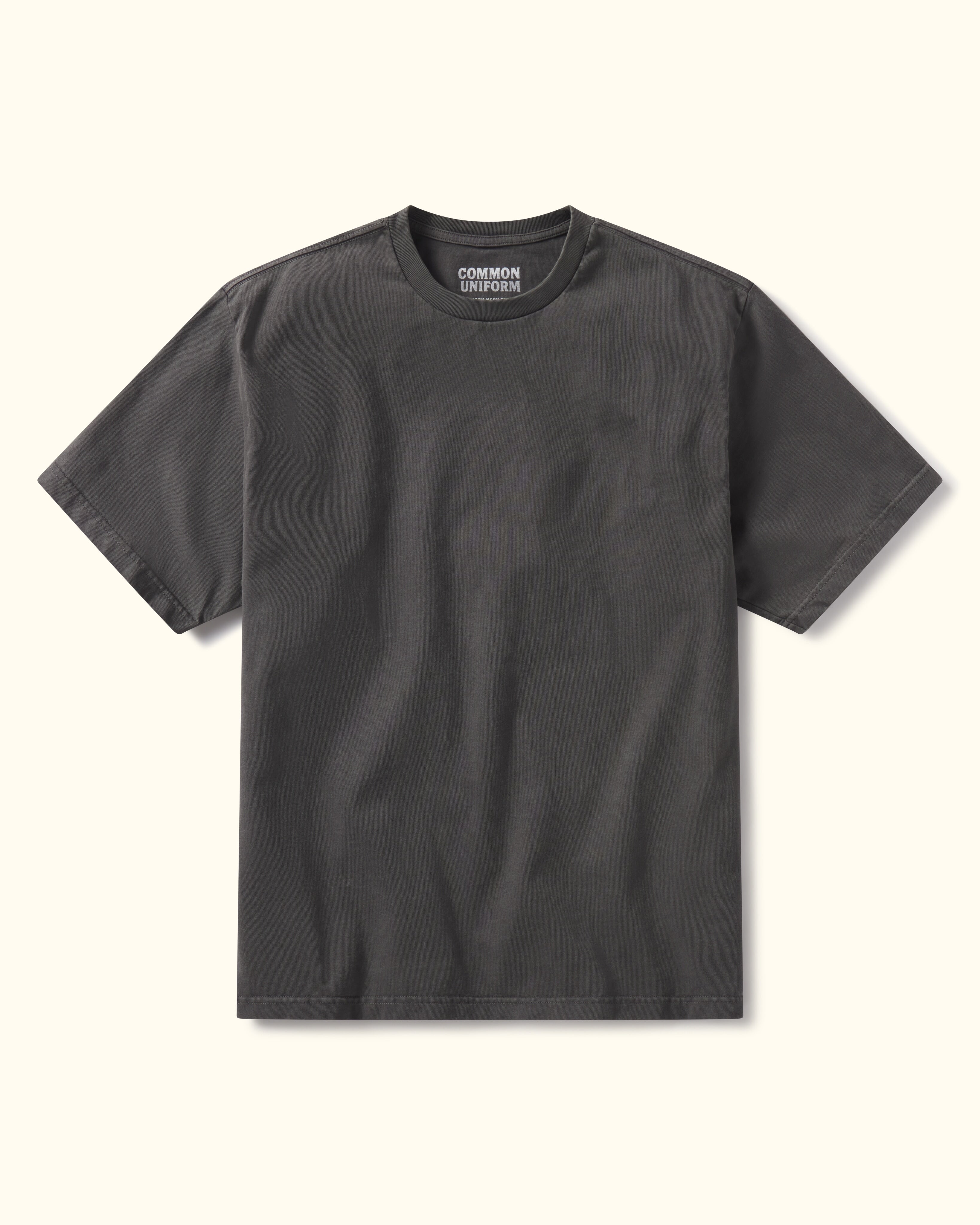 Steel grey t-shirt with 'Common Uniform' logo on a beige  background