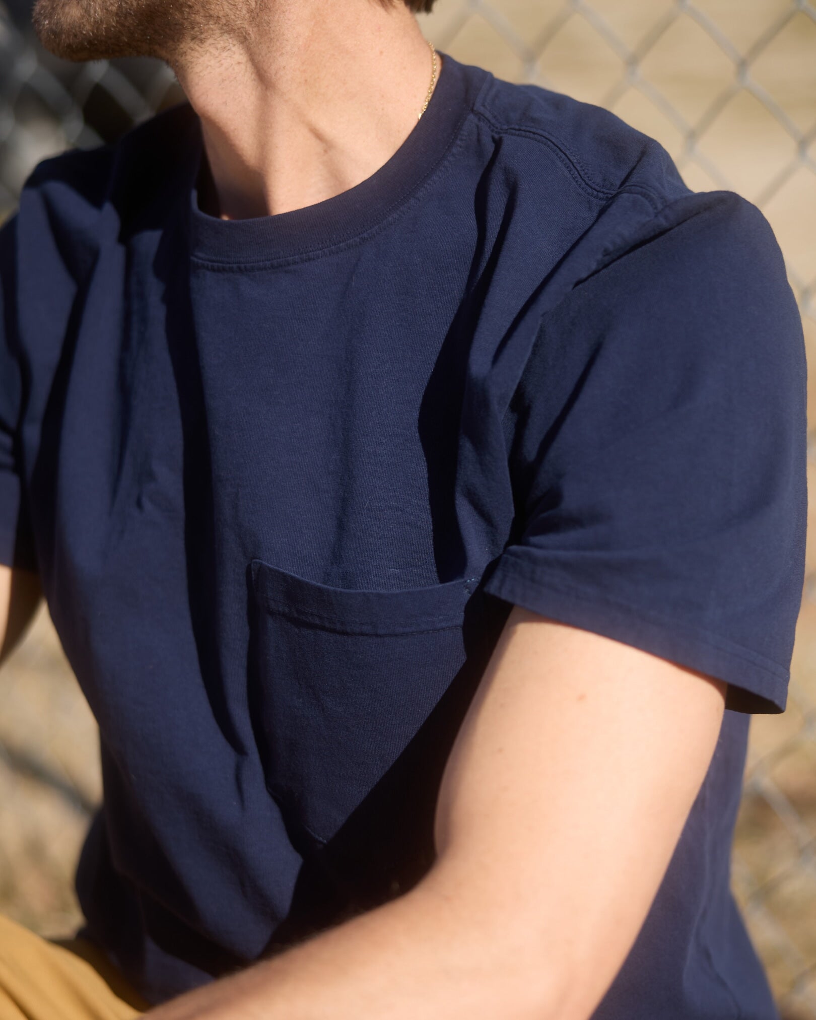 Person wearing a navy blue t-shirt with a blurred background. Model is 6'1", 170lbs wearing size L