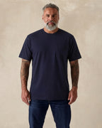Man wearing a navy blue t-shirt and jeans against a beige background. Model is 5'11", 210lbs wearing size XL
