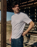Man wearing a white t-shirt and blue jeans standing outdoors. Model is 6'1", 170lbs wearing size L
