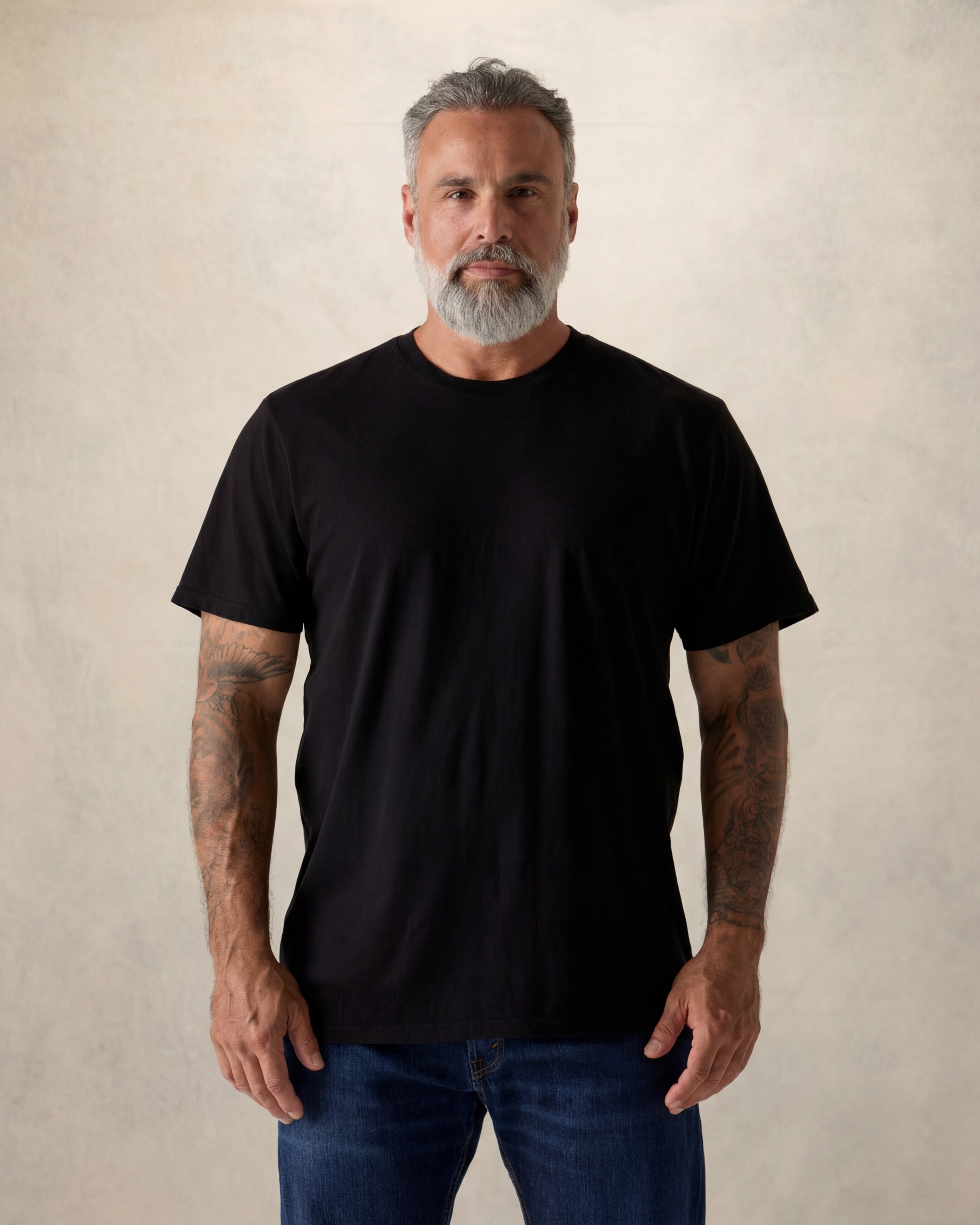 Man wearing a black t-shirt against a beige background. Model is 5'11", 210lbs wearing size XL